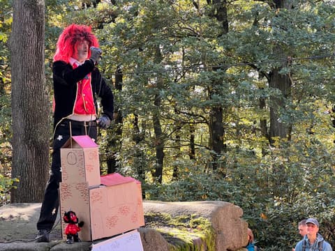 Als Teufel verkleidete Figur neben dem Wettkampfstein im Wald
